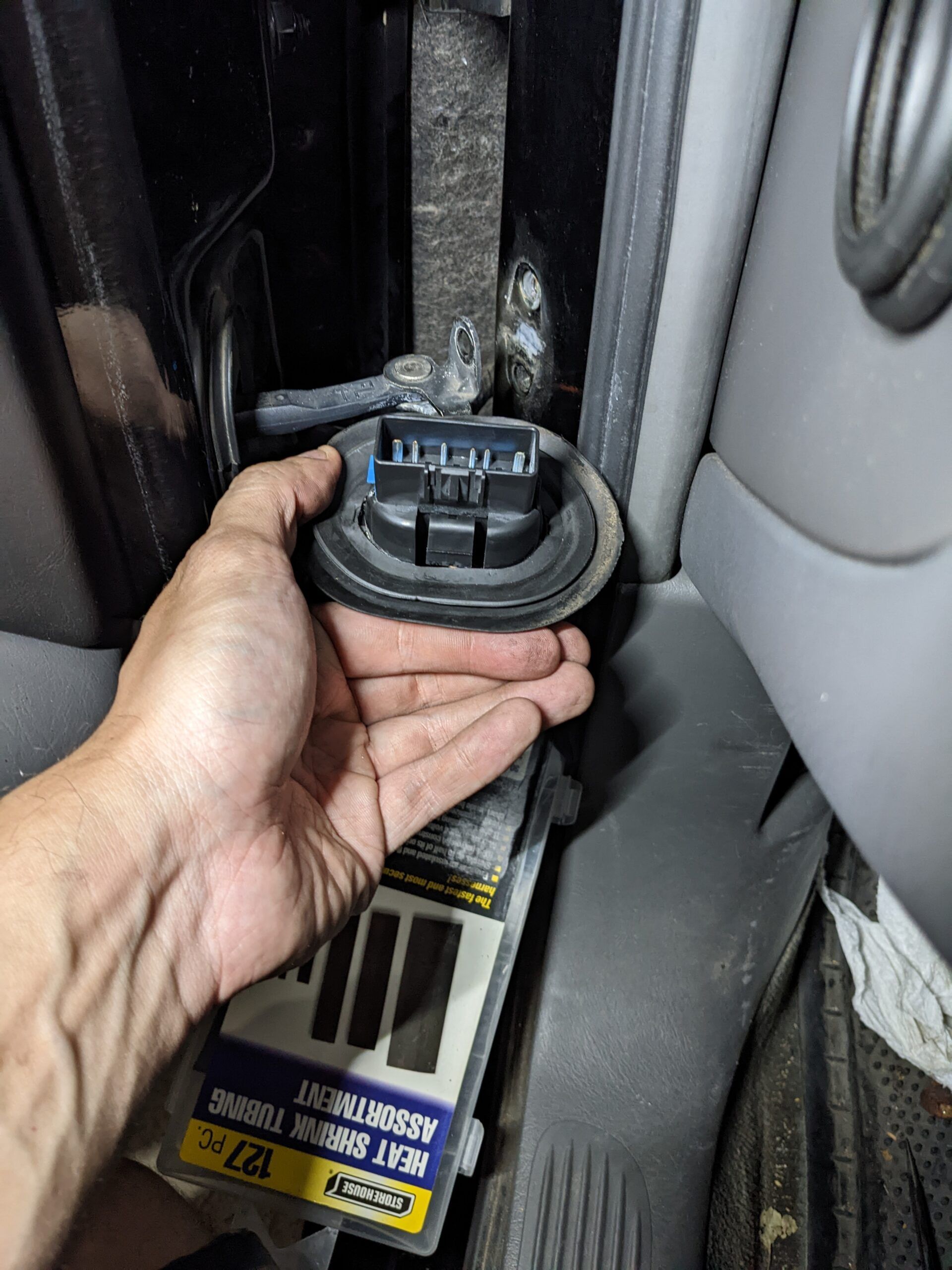 A person is holding a piece of equipment in their hand in a car.