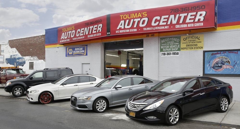 A row of cars are parked in front of a tolima 's auto center.