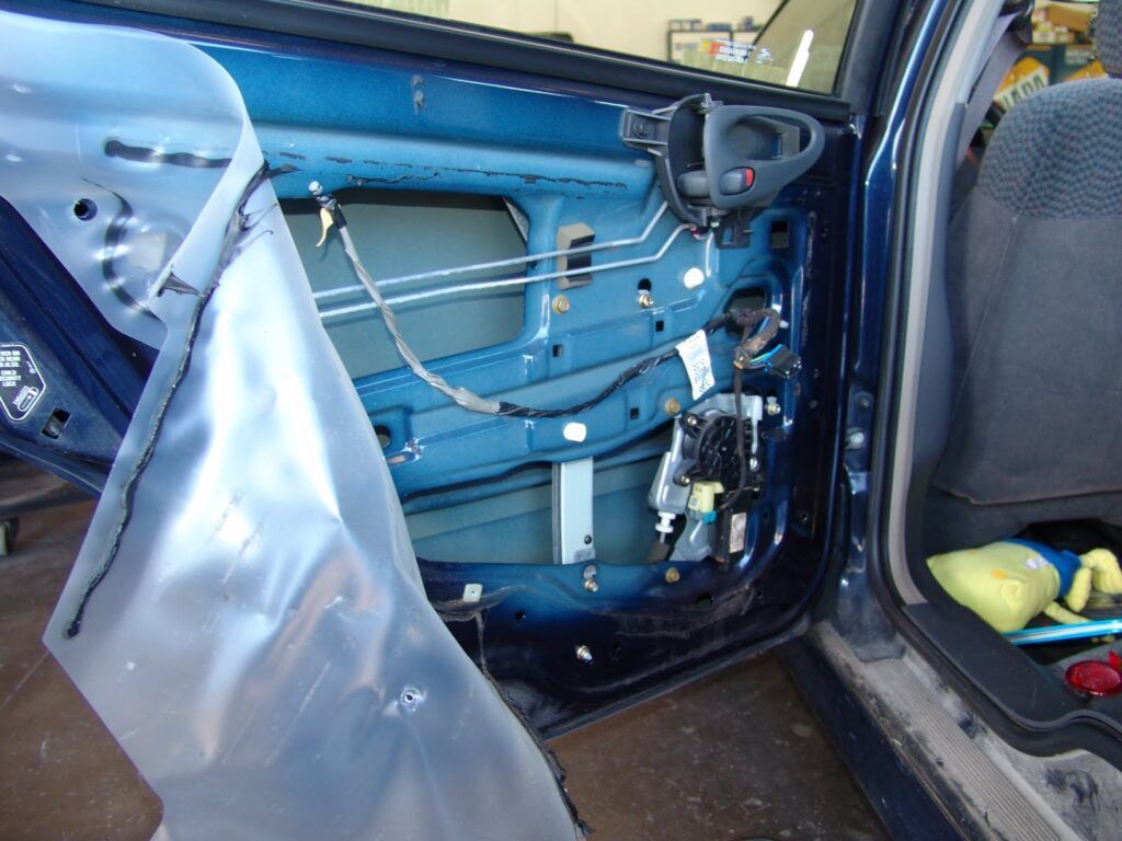 The inside of a blue car with a plastic bag covering the door