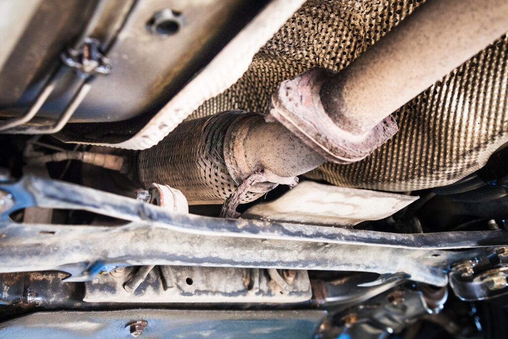 A close up of the underside of a car showing the exhaust pipe.