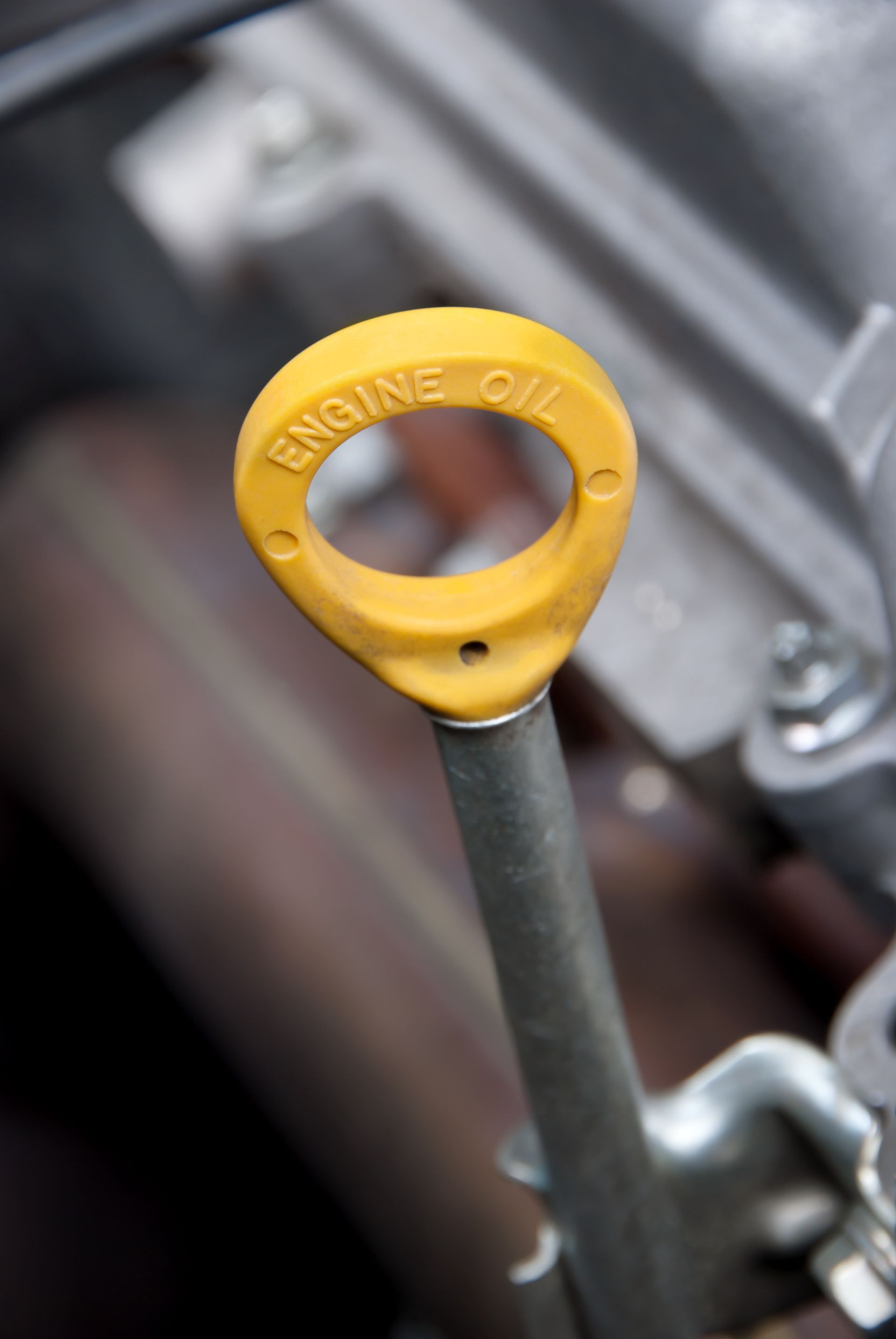 A close up of an engine oil dipstick on a car engine.