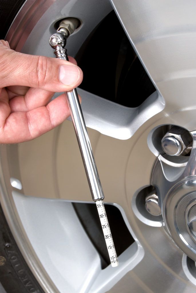 A person is checking the air pressure on a tire