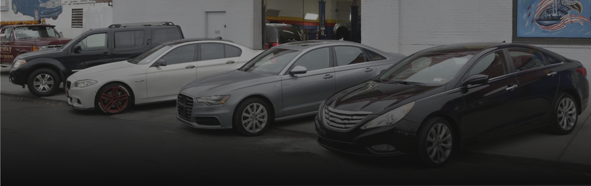 A row of cars are parked in front of a car dealership.