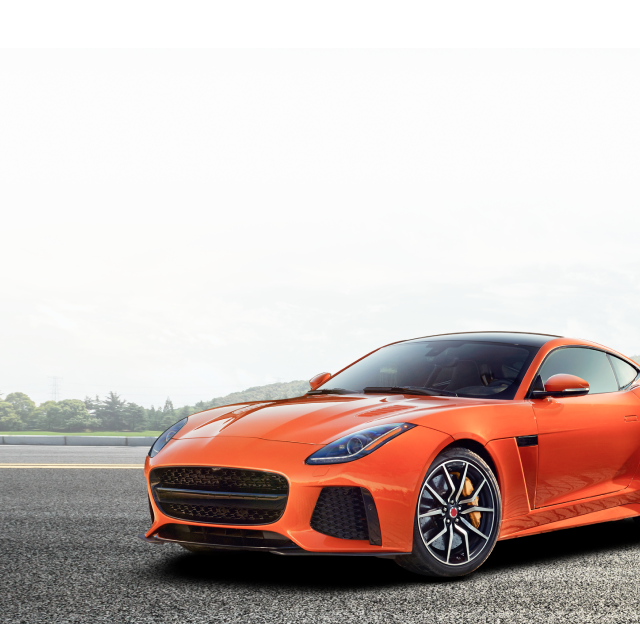 An orange sports car is parked on the side of the road.