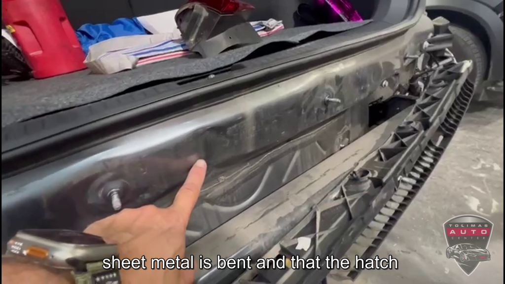 A person is pointing at a piece of metal on a car.
