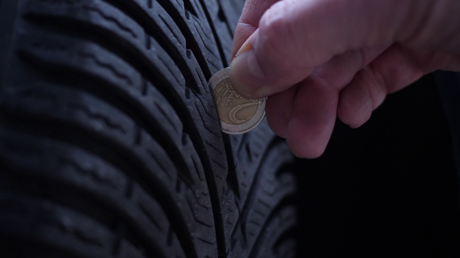 A person is putting a coin in a tire.