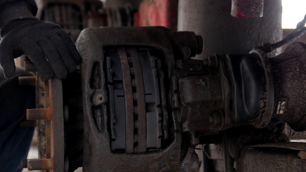 A person is fixing a brake caliper on a truck.