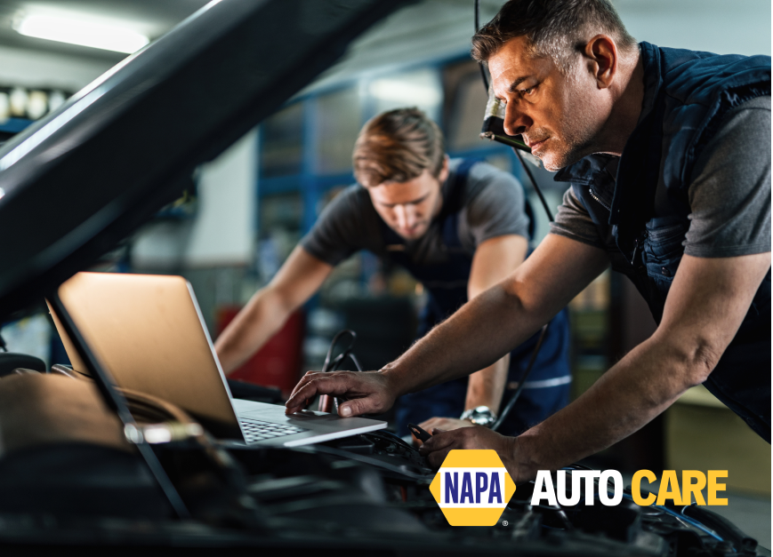 Two men are working on a car with a laptop.