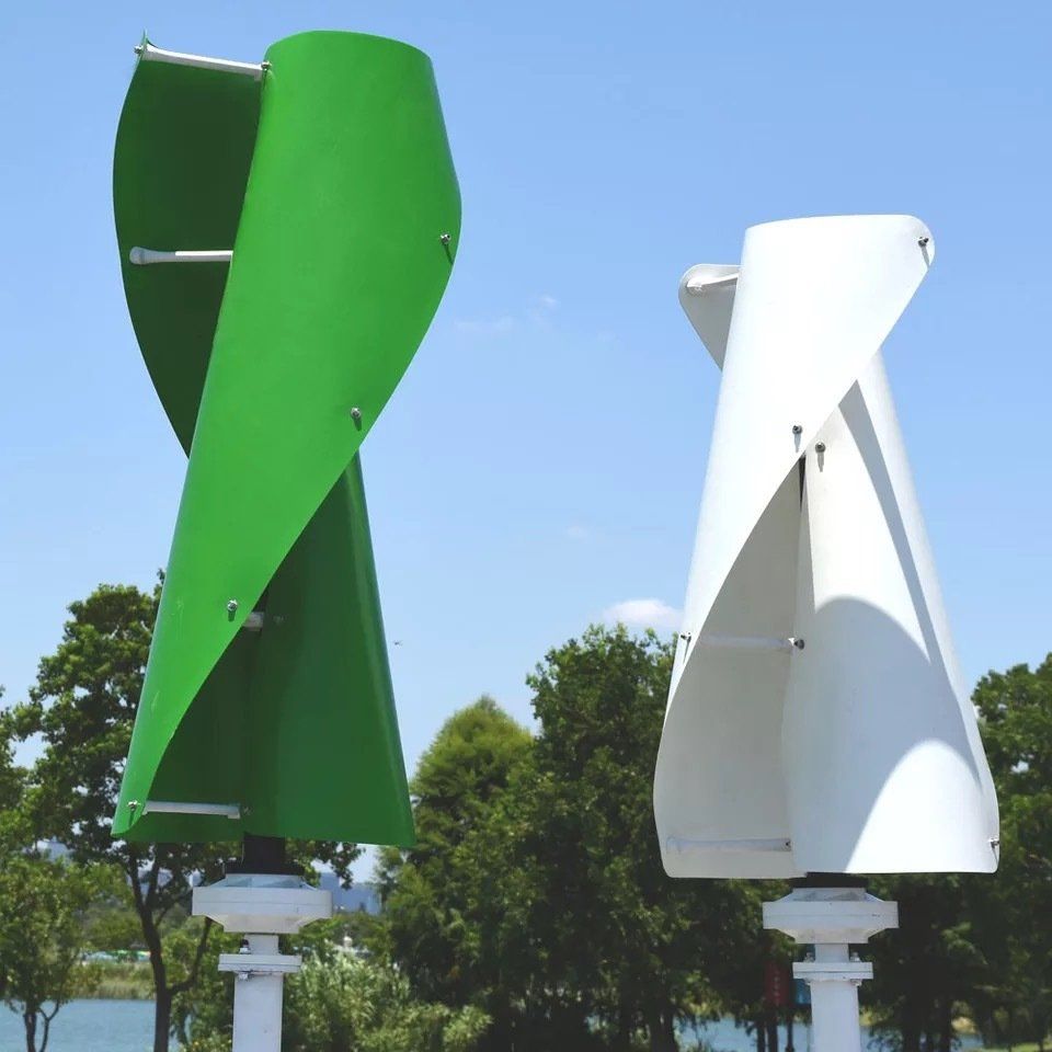 Een groene en een witte windturbine met bomen op de achtergrond
