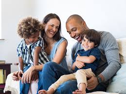 Een gezin zit samen op een bank en lacht.