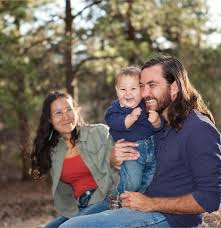 Een man en een vrouw zitten op een bankje en houden een baby vast.