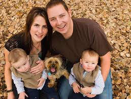 Een gezin met twee baby's en een hond poseert voor een foto.