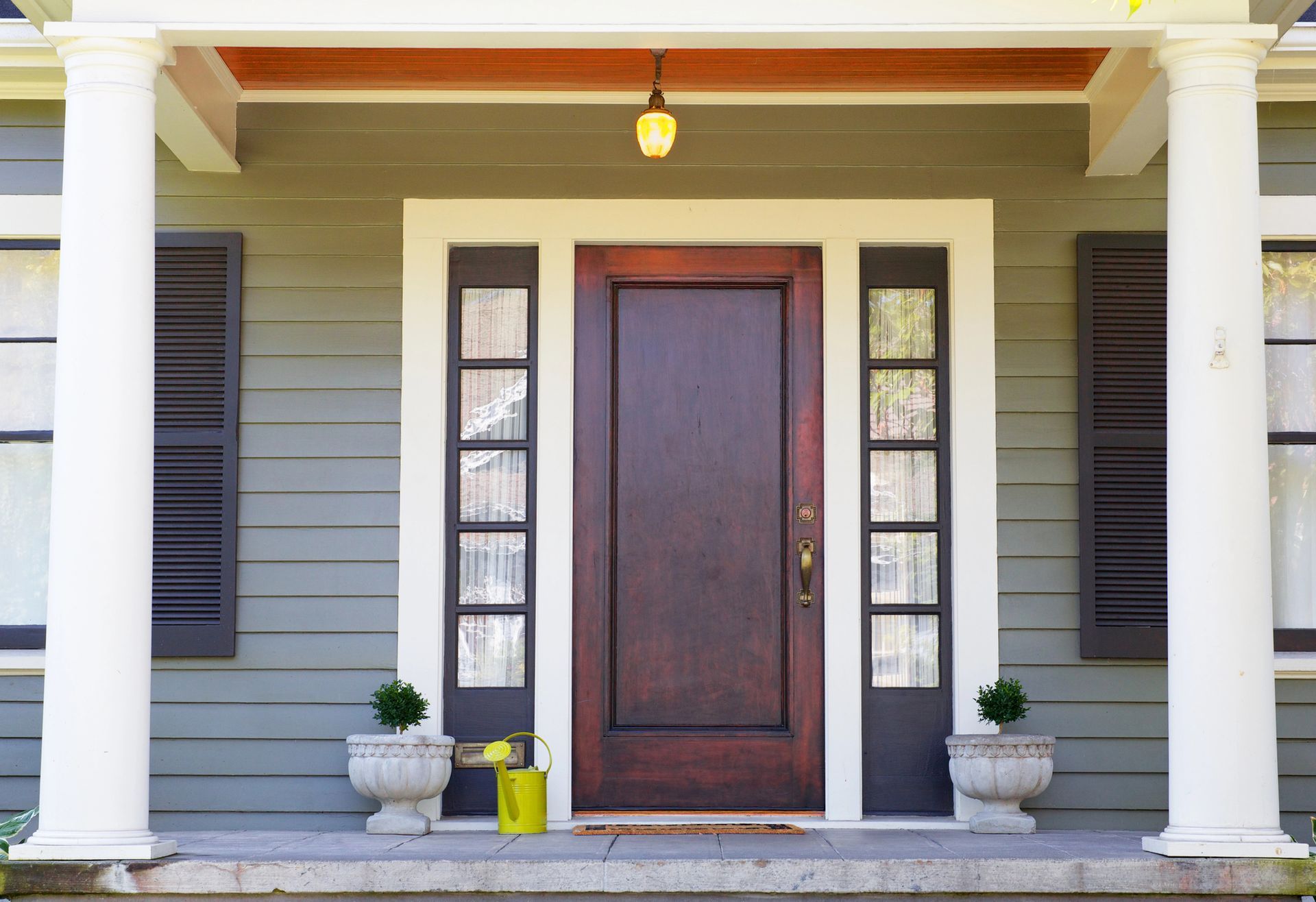 The front door of a house with a porch and a wooden door