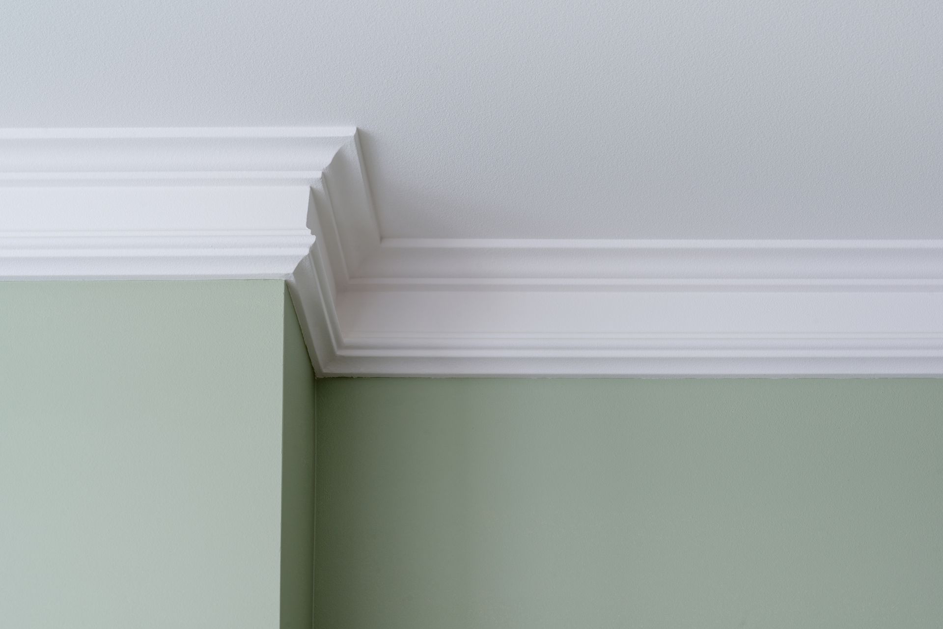 A white molding on the ceiling of a room with green walls.