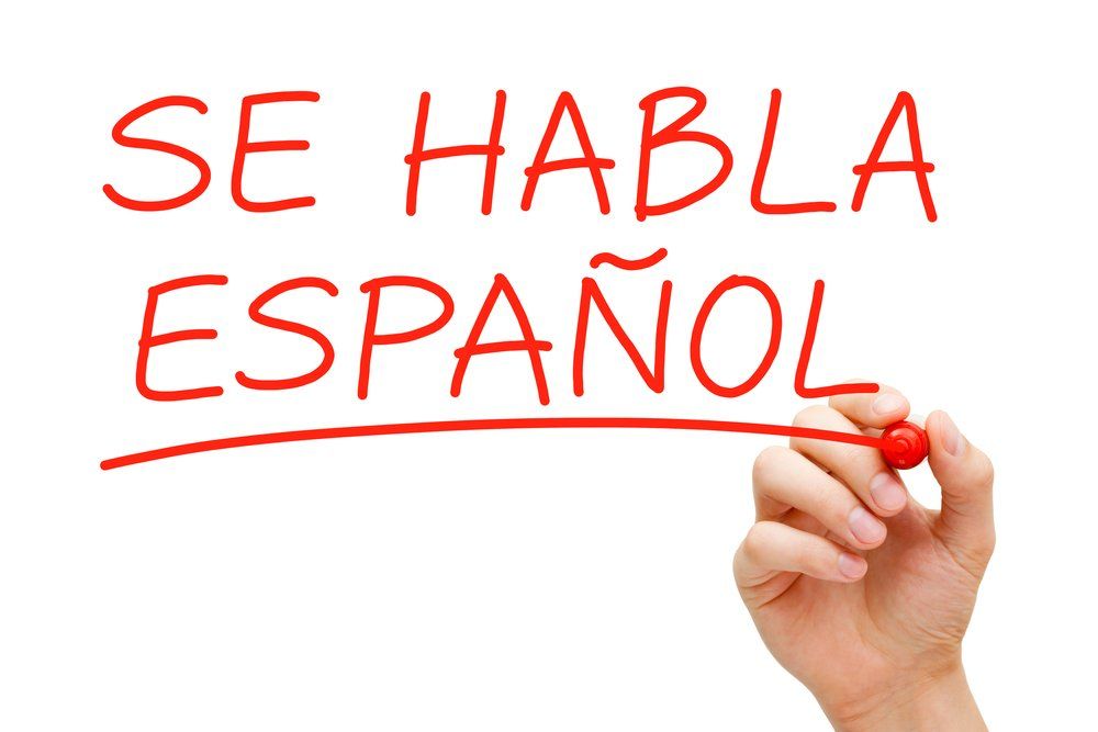 A hand is writing se habla espanol with a red marker