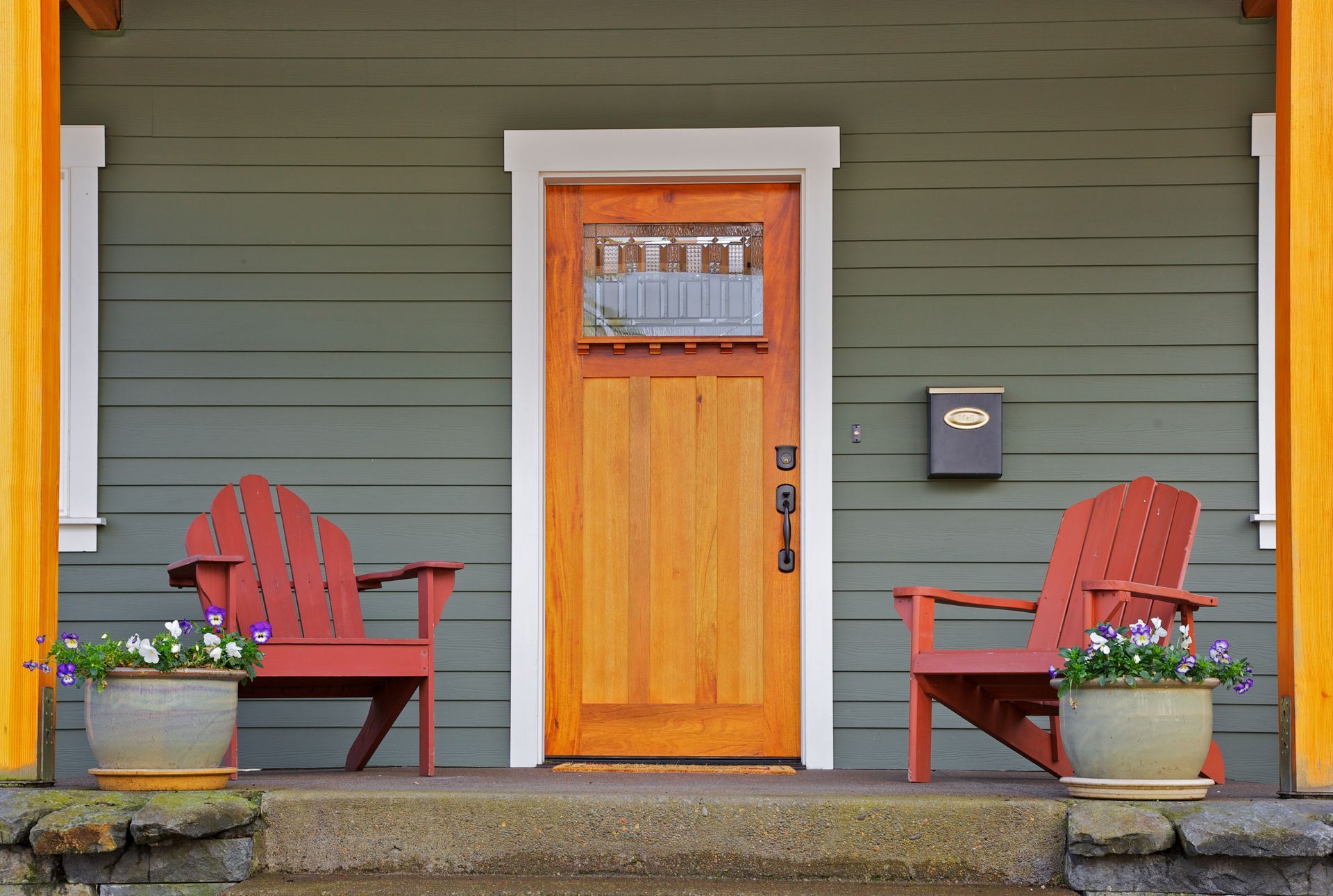 A porch with two red chairs and a mailbox