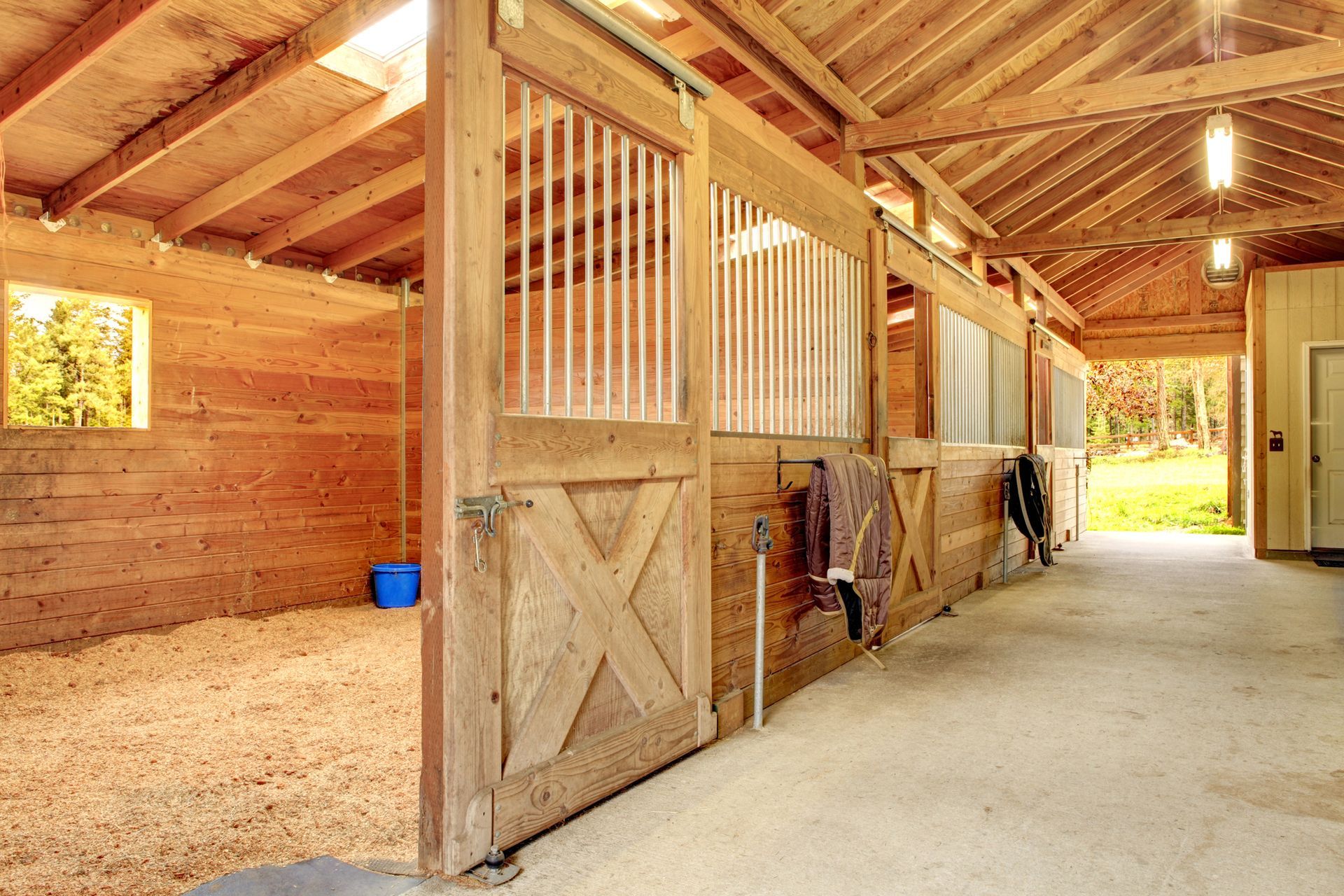 A row of wooden horse stables with the doors open.