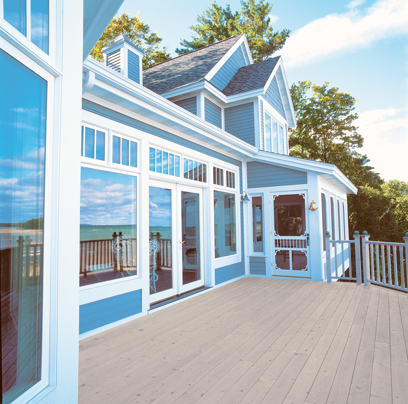 A blue and white house with a large deck overlooking the ocean