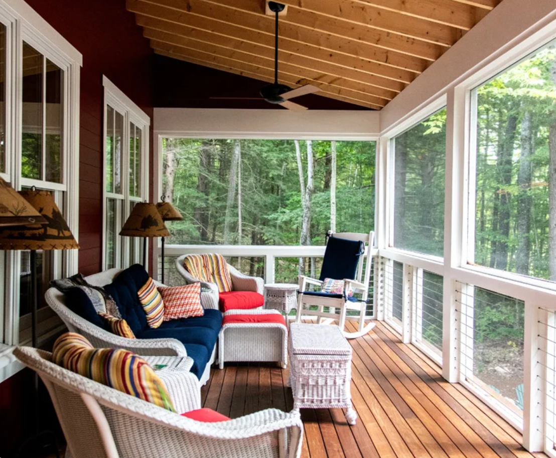 A screened in porch with a couch and chairs