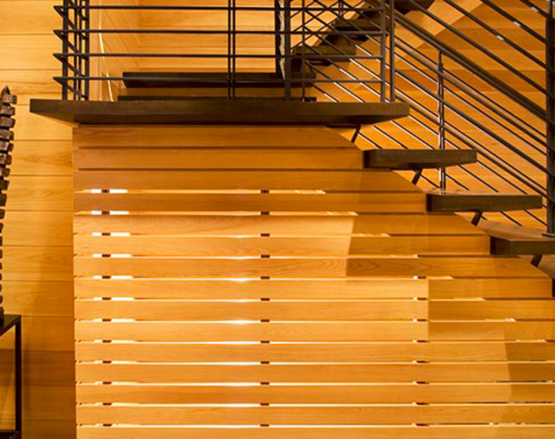 A wooden staircase with a metal railing and a wooden wall behind it