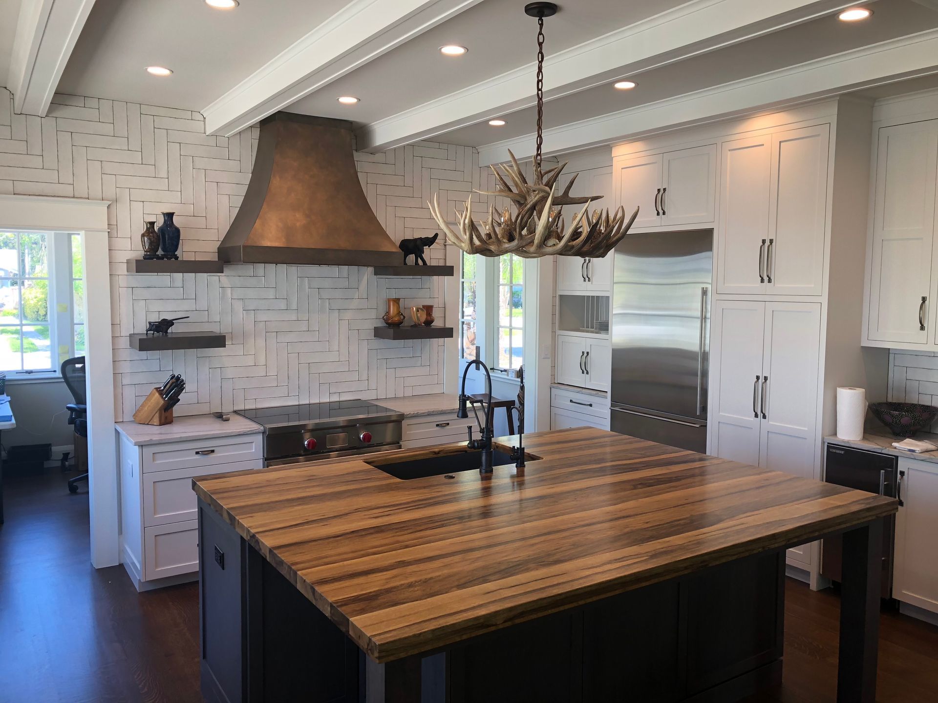 A kitchen with a large wooden island and a chandelier hanging from the ceiling.