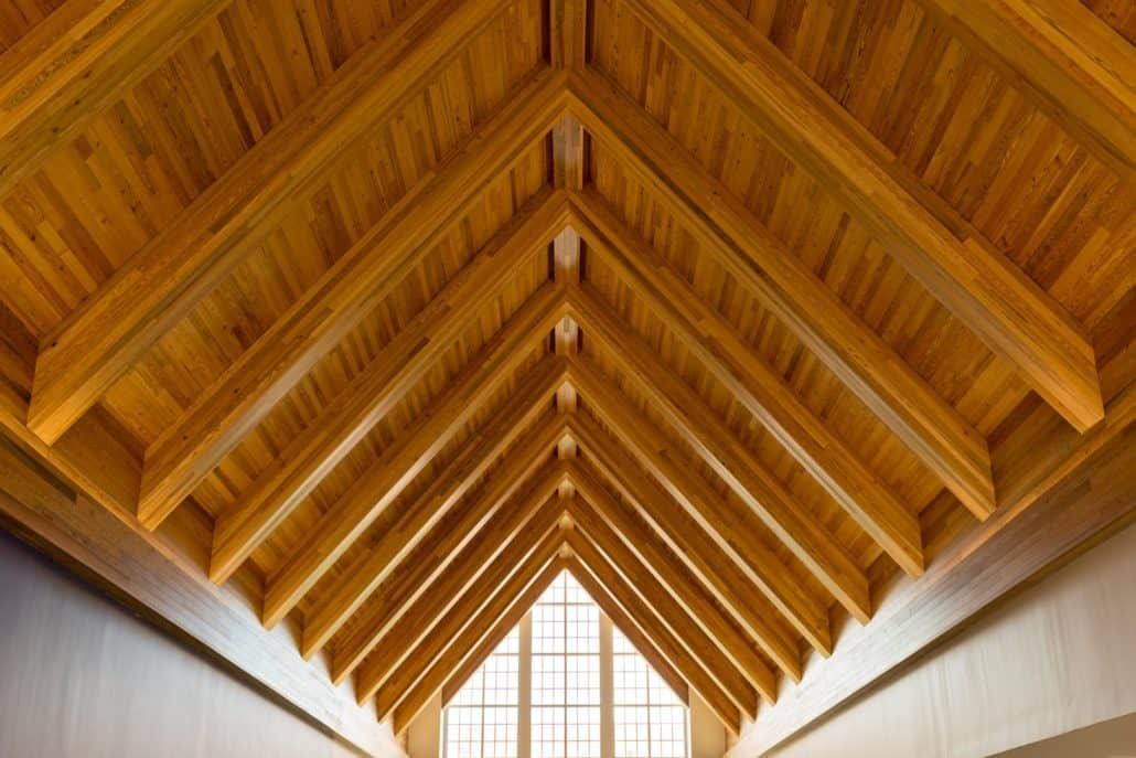 Wooden ceiling with angled beams, light streaming in from a window below.
