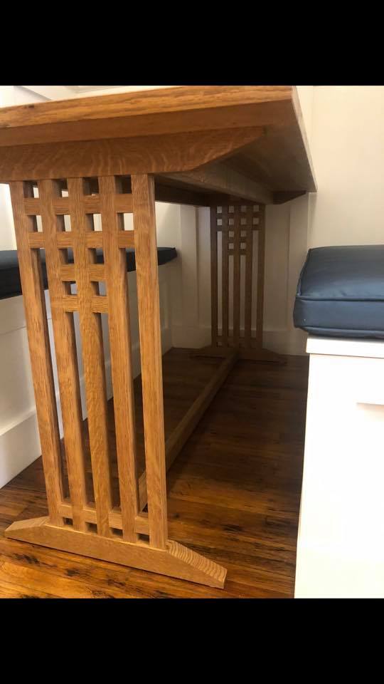 A wooden table is sitting on a wooden floor next to a bench.