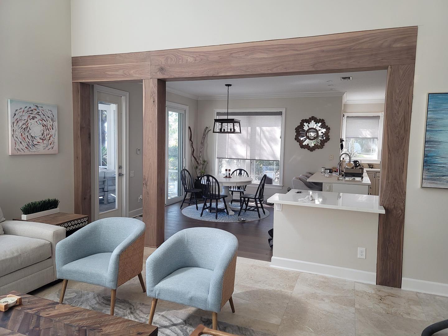 A living room with a wooden beam between the dining room and kitchen.
