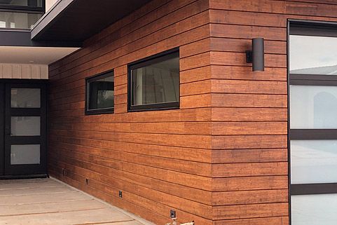 A house with a wooden siding and a glass garage door.