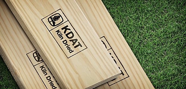 Two pieces of wood are stacked on top of each other on a grassy field.