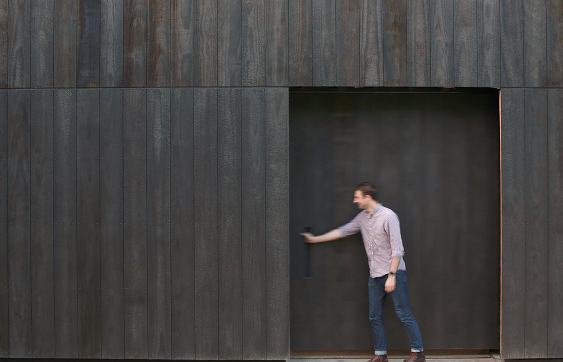 A man is standing in front of a wooden building.