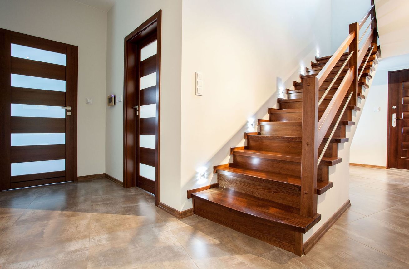 A wooden staircase with lights on the steps in a hallway.