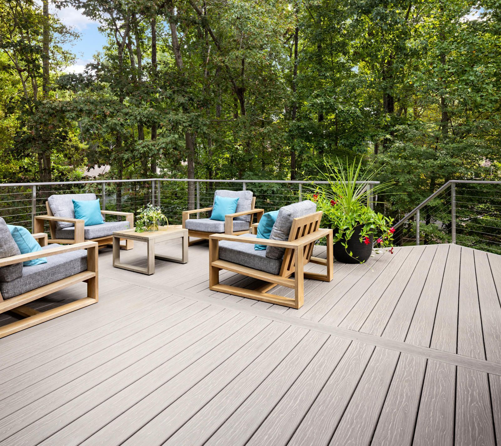 A wooden deck with chairs and a table on it surrounded by trees.