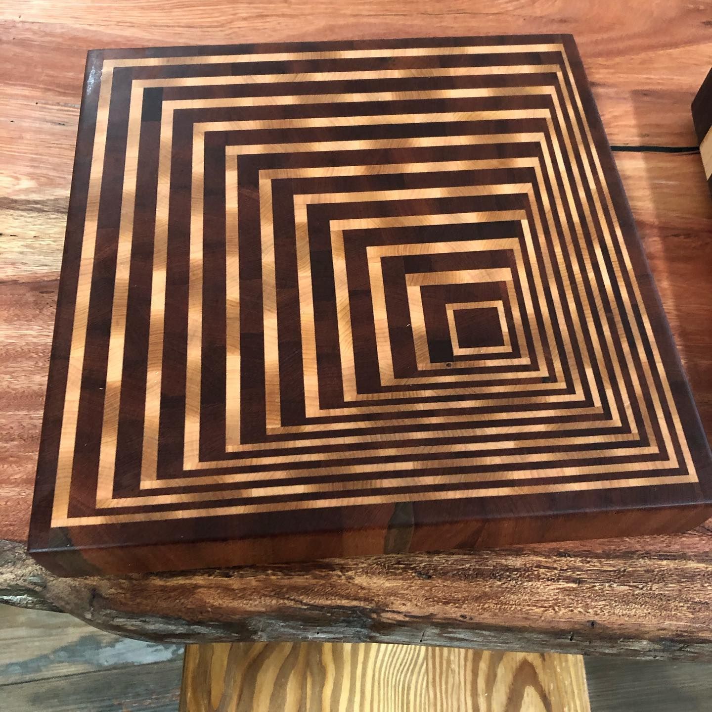 A wooden cutting board with an optical illusion design on it