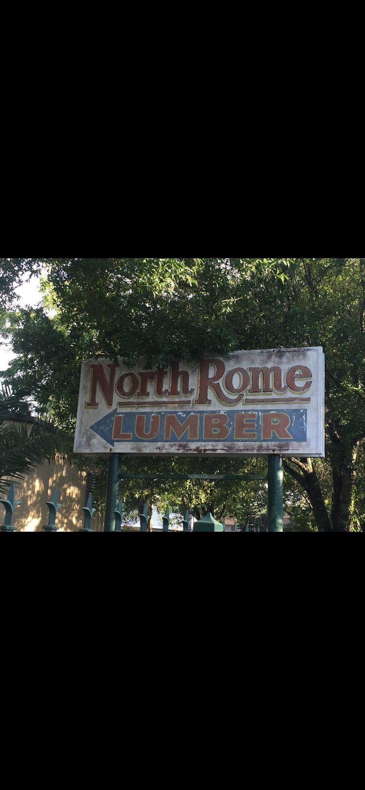 A sign for north rome coaster is surrounded by trees.