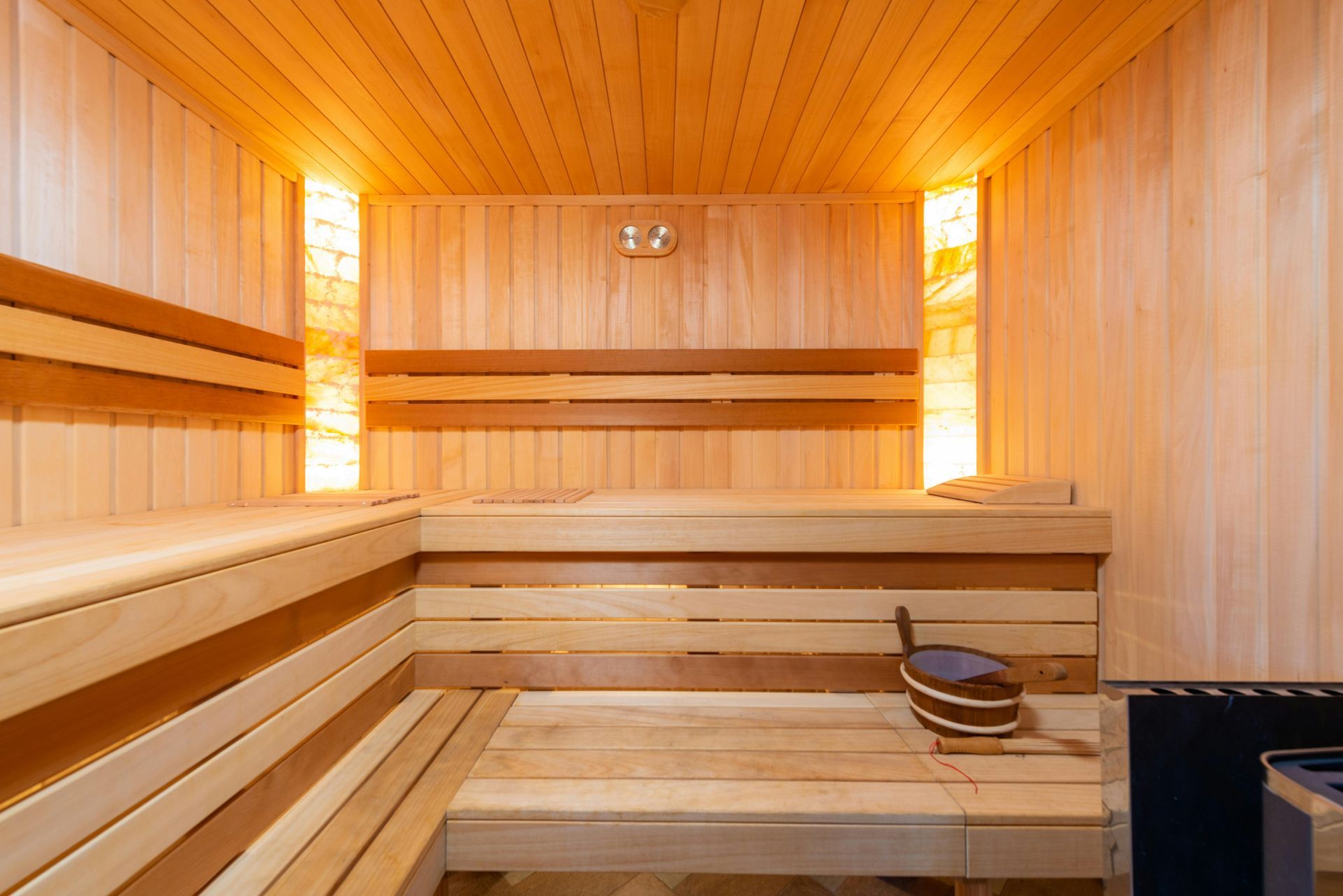 A wooden sauna with a bucket on the floor.