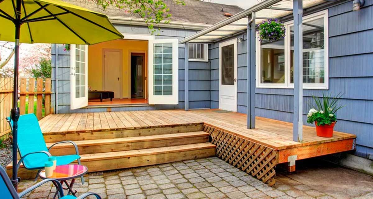 A wooden deck with a bench in the background and trees in the background.