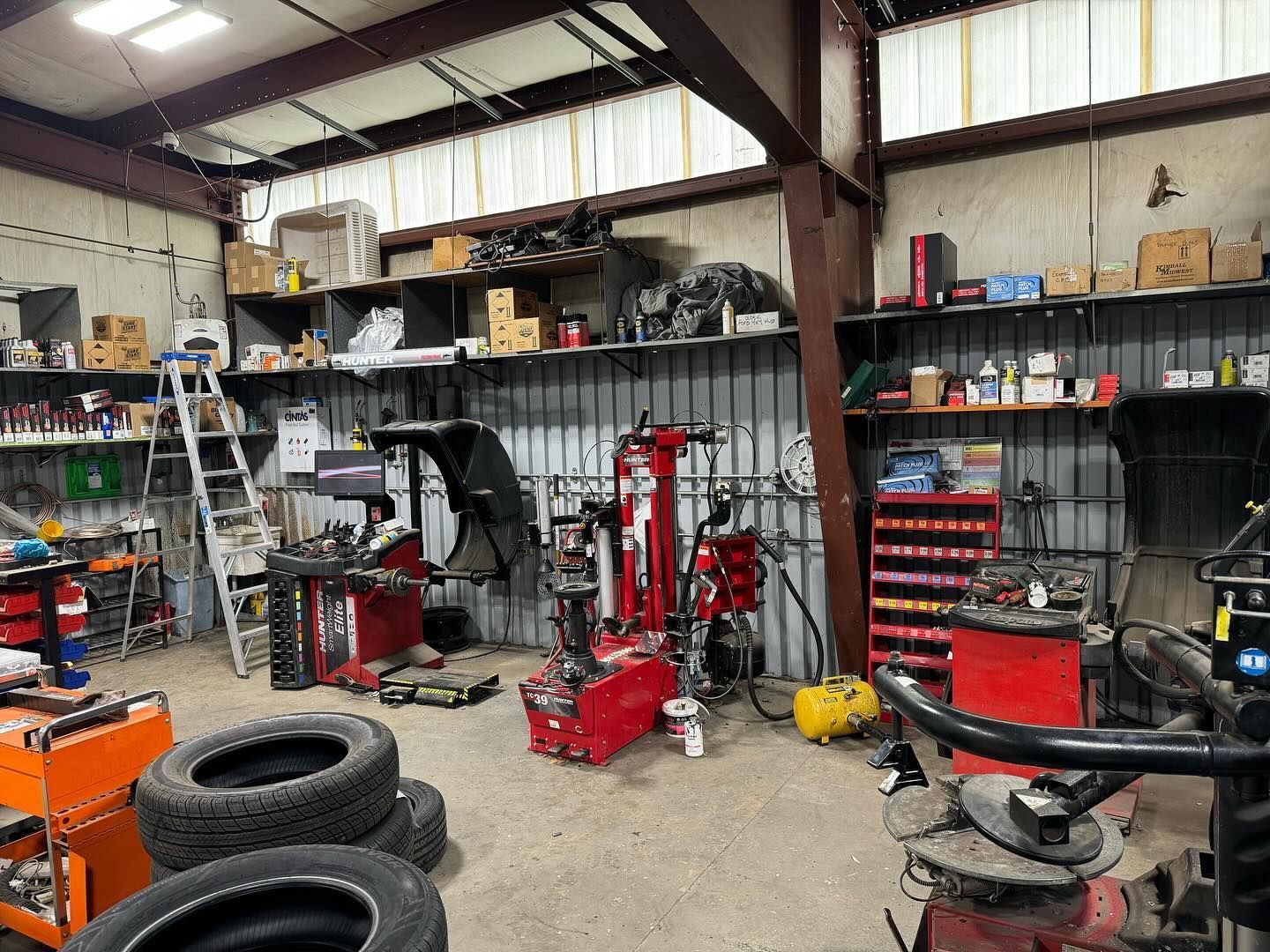 A tire repair shop interior with machinery, tools, shelves, and tires. | Dave Muller Automotive & Trailer
