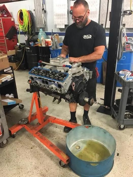 Mechanic working on an engine mounted on a stand in a garage. | Dave Muller Automotive & Trailer