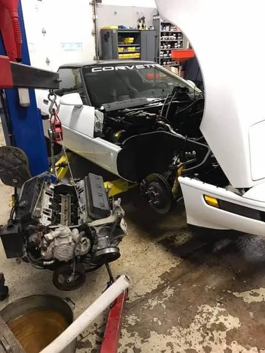 White Corvette undergoing repair in a garage; engine removed and on the floor. | Dave Muller Automotive & Trailer