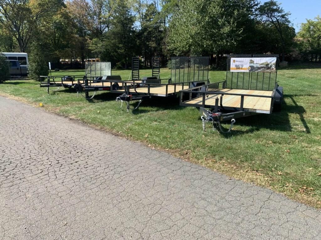 Three black trailers parked on grass next to a paved path; trees in background. | Dave Muller Automotive & Trailer