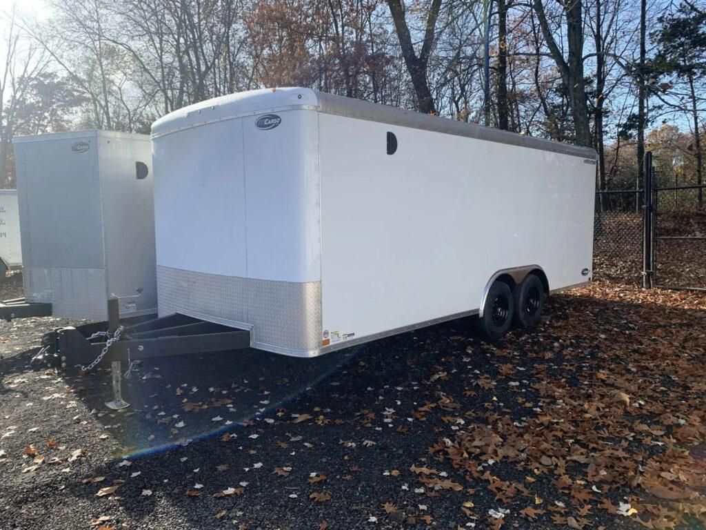 White cargo trailer with black tires, parked outdoors in front of trees. | Dave Muller Automotive & Trailer