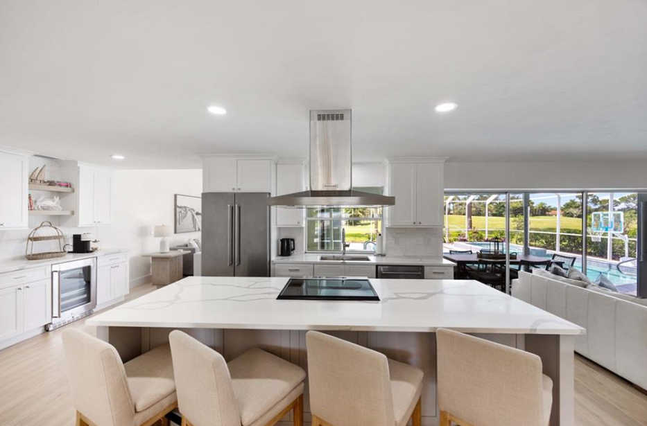 Bright, modern kitchen with large island, stainless steel appliances, and a view of a pool.