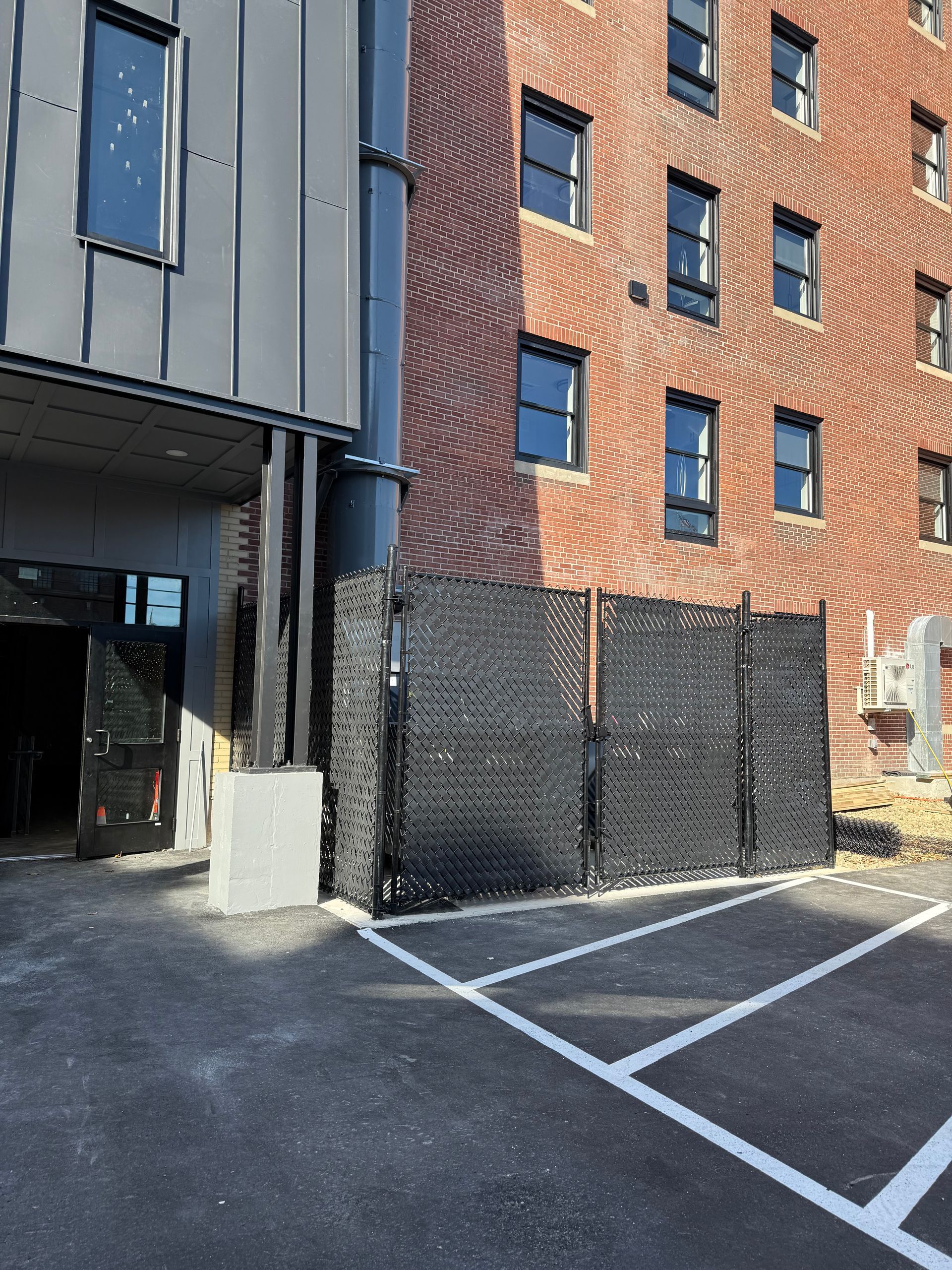 8ft tall building compactor enclosure with a double drive 12ft gate opening and black diagonal fence tape pic #1
