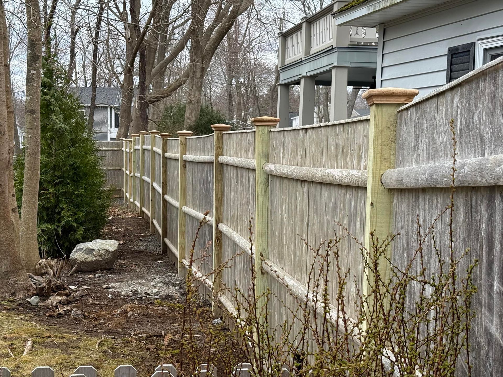 Wooden fence along a yard with a house visible in the background.
