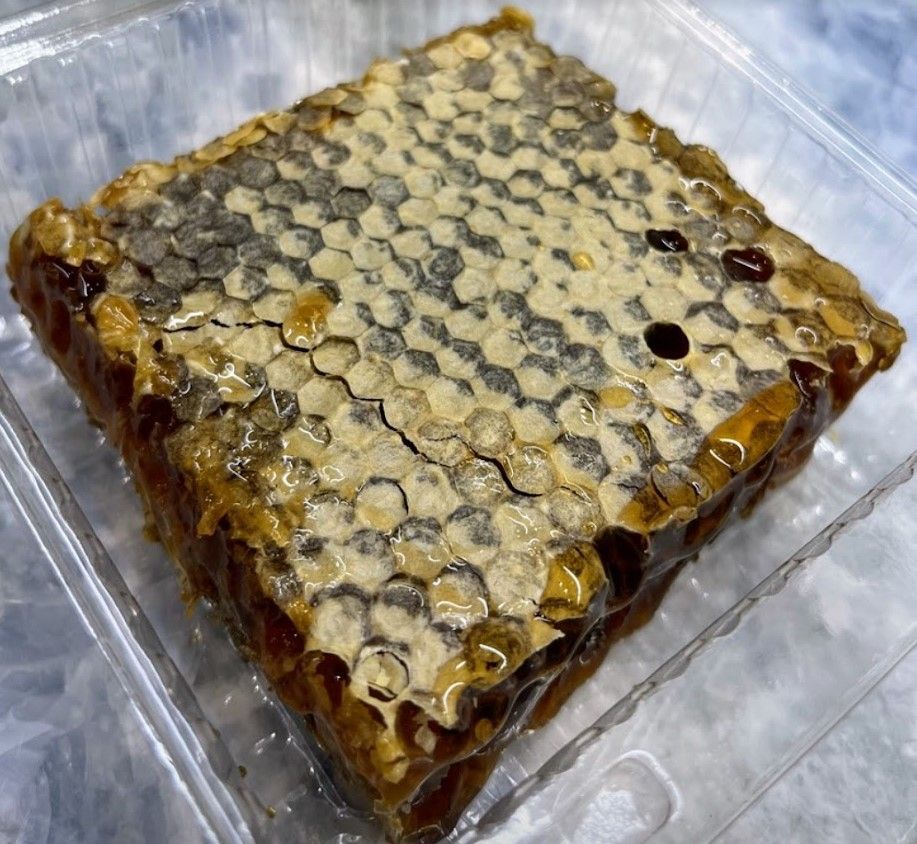 Close-up of golden honeycomb dripping with raw, unfiltered honey.