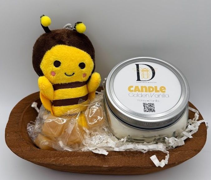 Hand-carved wooden dough bowl gift set containing a Honey Vanilla 8 oz mason-lid candle, a small plush bee keychain, and wrapped honey drops nestled in paper shred