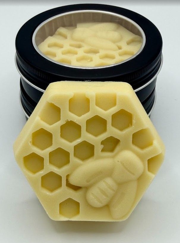 Stack of reusable tins with beeswax honeycomb lotion bars, showing detailed hexagon and bee design on the bar
