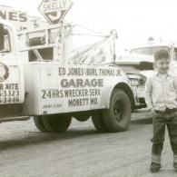 A tow truck from Ed Jones Garage in Monett, MO, with a boy posing in front of it.