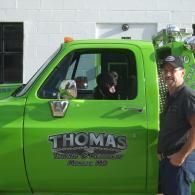Man and dog in a green tow truck; the truck says